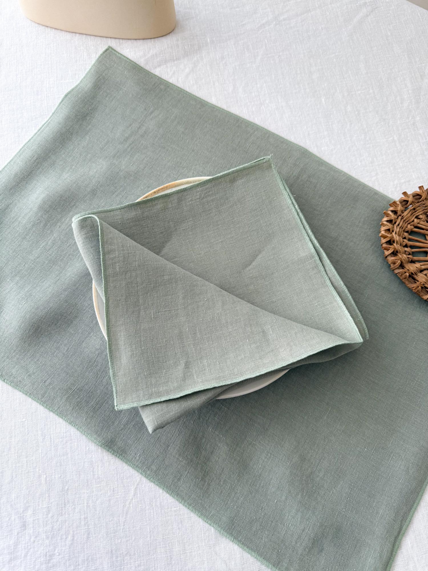 Serviette de table en lin vert sauge avec ourlet roulé